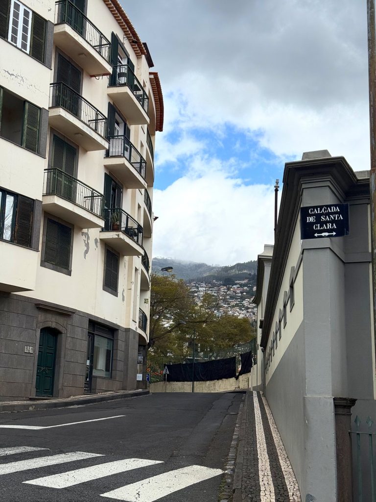 Straßenschild der Calçada de Santa Clara an einer Hausecke neben einem Fußgängerüberweg