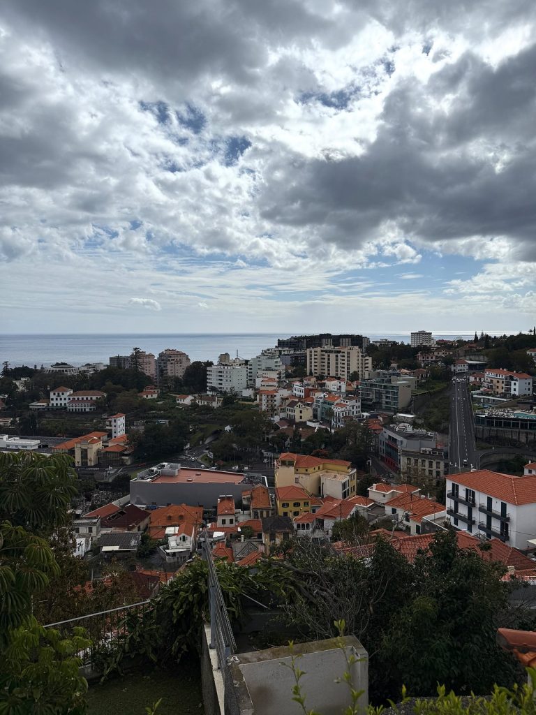 Dunkle Wolken über den Dächern von Funchal, in der Ferne das Meer