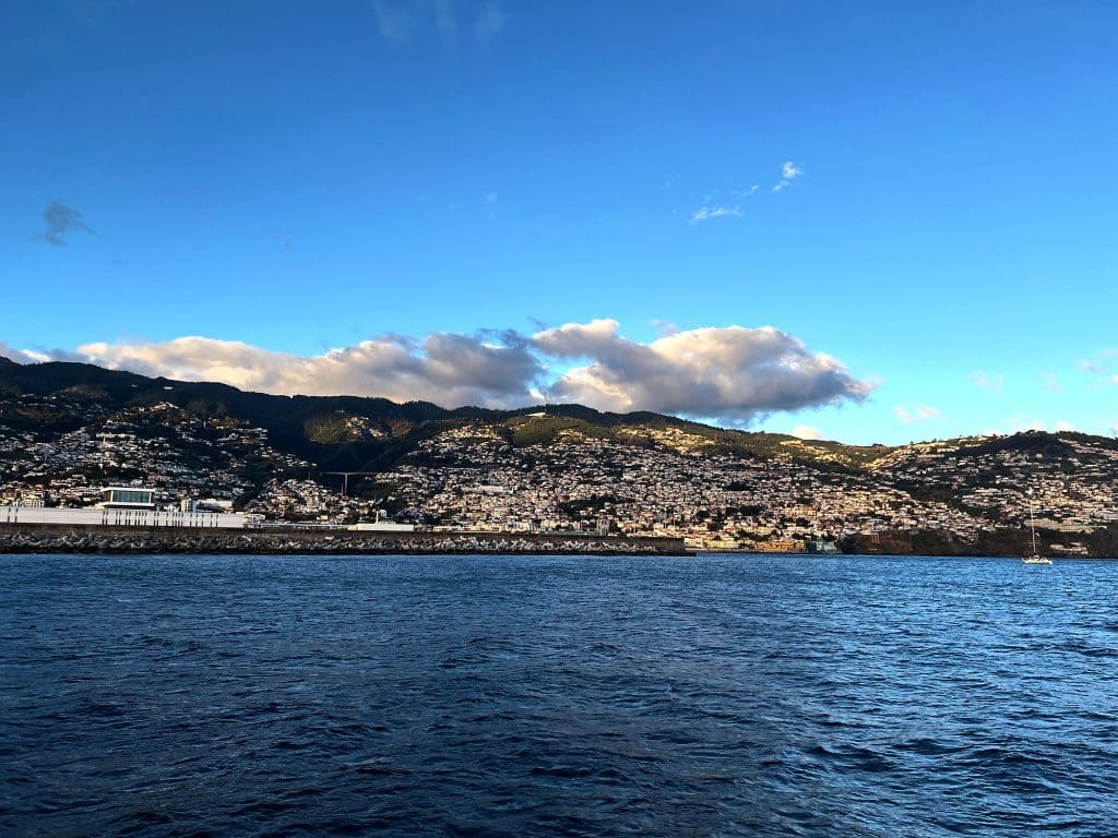 Funchal vom Meer aus, mit Häusern an den Hängen über dem Ufer