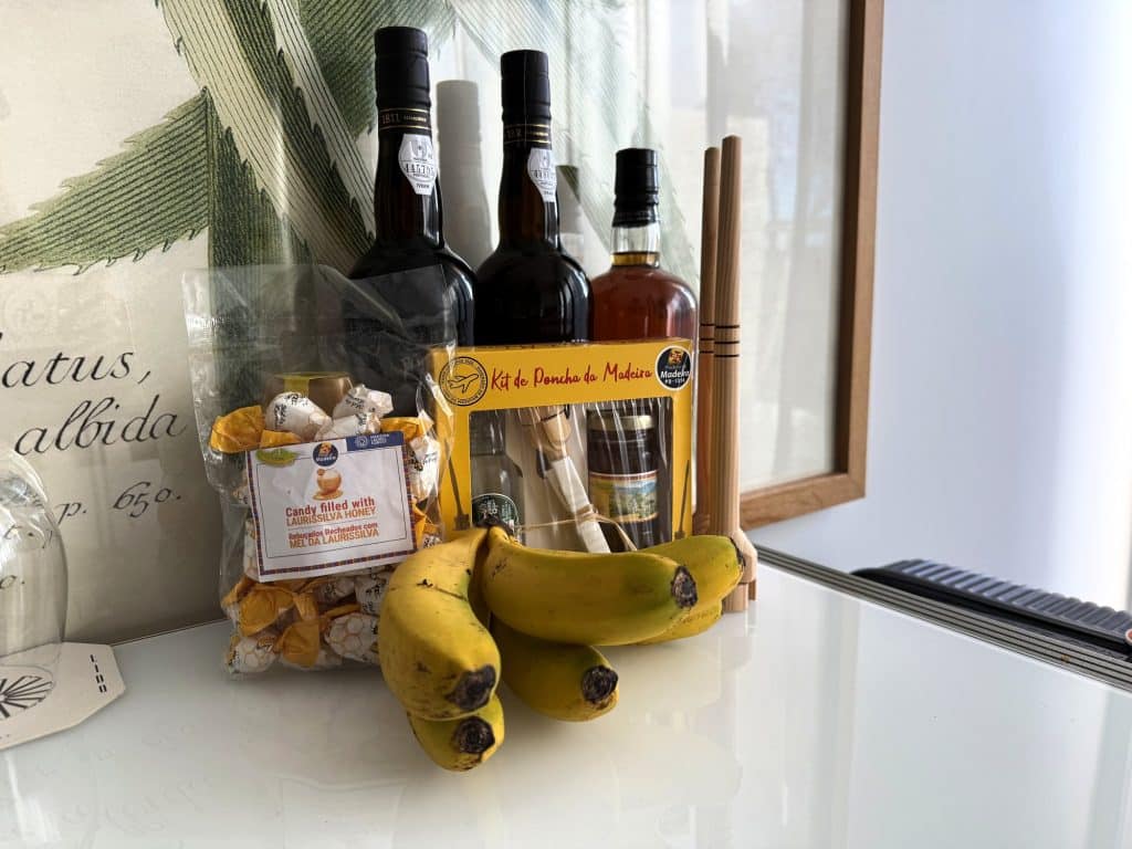 Souvenirs aus Madeira am Fenster eines Hotelzimmers: Flaschen, Bananen und Süßigkeiten