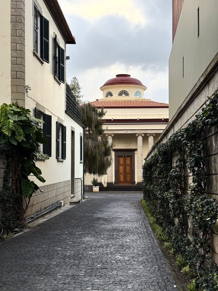 Eine gepflasterte Straße, die zu einer runden Kirche mit roter Kuppel und Säulen führt