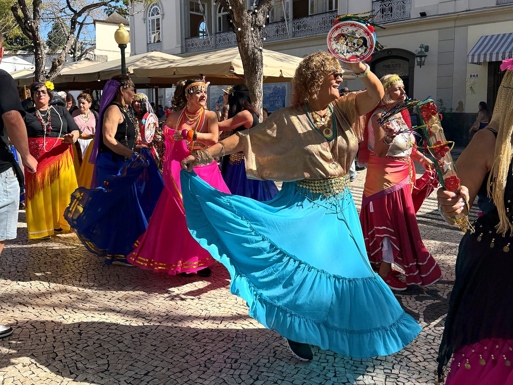 Tänzerinnen in bunten Röcken wirbeln beim Carnaval Solidário über die Avenida Arriaga in Funchal