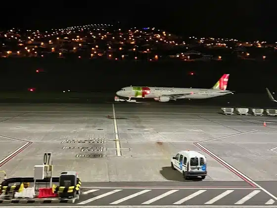 Ein TAP-Flugzeug nachts auf dem Vorfeld des Flughafens Madeira, dahinter Lichter der Häuser am Hang
