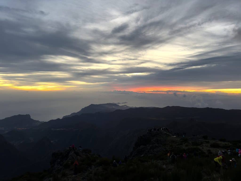 Morgendämmerung über den Wolken am Pico do Arieiro, ein orangefarbener Lichtstreifen am Horizont