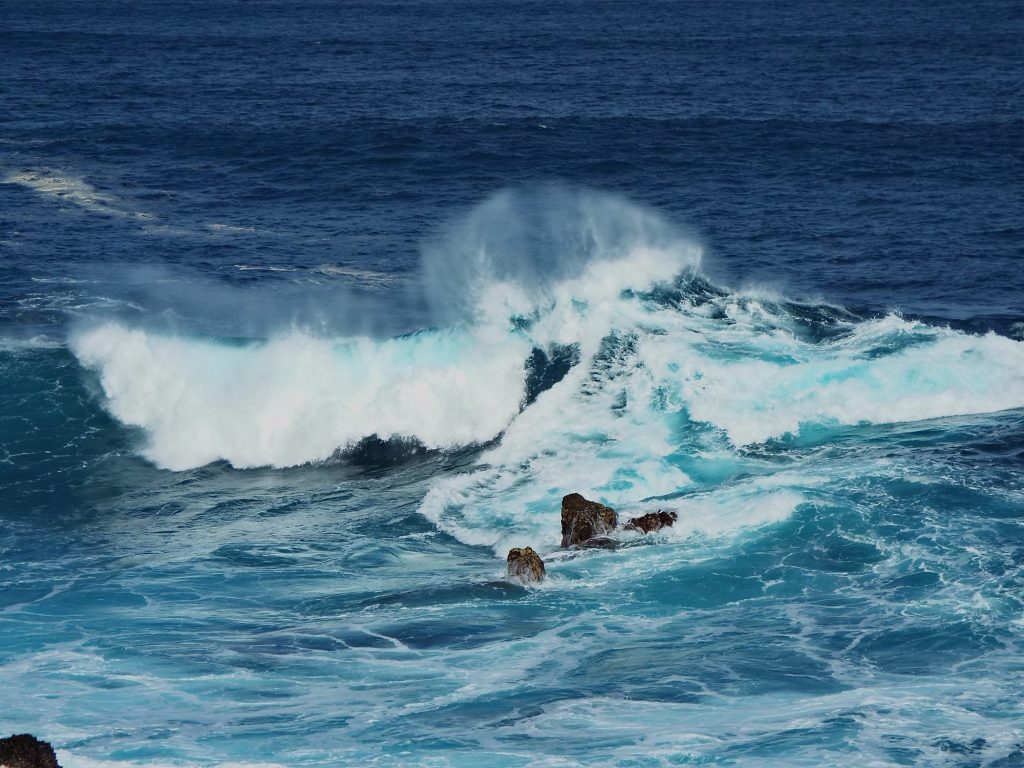 Eine große Welle bricht an den Felsen bei den Pools in Porto Moniz