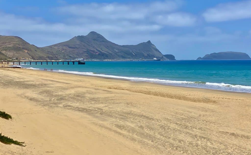 Breiter Sandstrand auf Porto Santo mit der Mole und der kleinen Insel Ilhéu de Baixo im Hintergrund