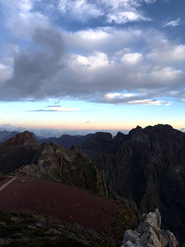 Ein roter Pfad auf dem Grat und die dunklen Gipfel des zentralen Gebirgsmassivs von Madeira