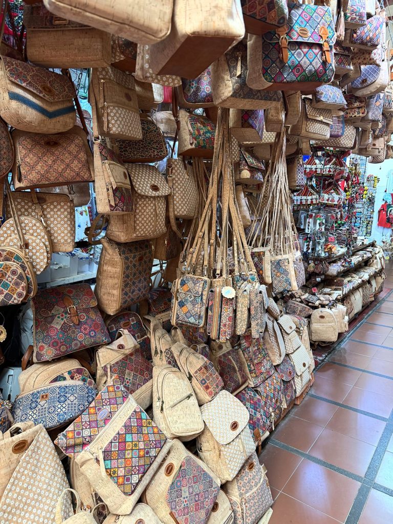 Ein Stand mit hängenden Korkhandtaschen und Rucksäcken in bunten Mustern