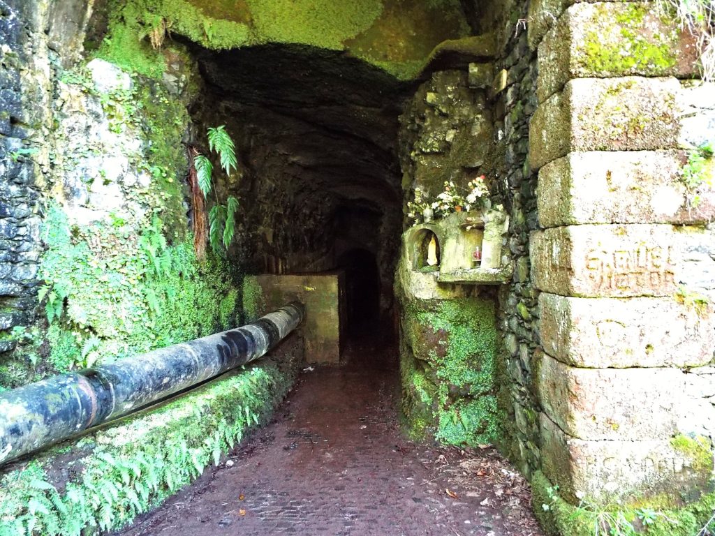 Eingang zu einem Steintunnel mit Wasserrohr am Weg in Rabaçal