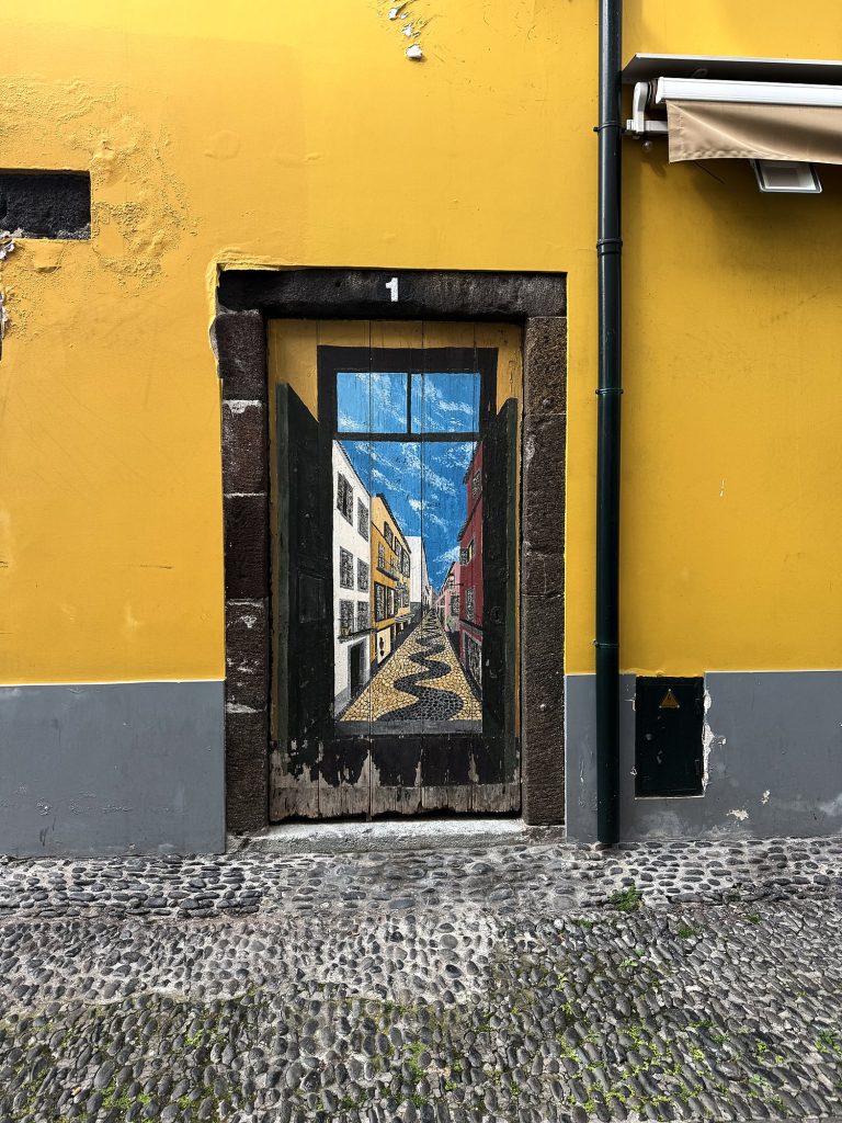 Eine bemalte Tür an einer gelben Fassade in der Zona Velha, Funchal